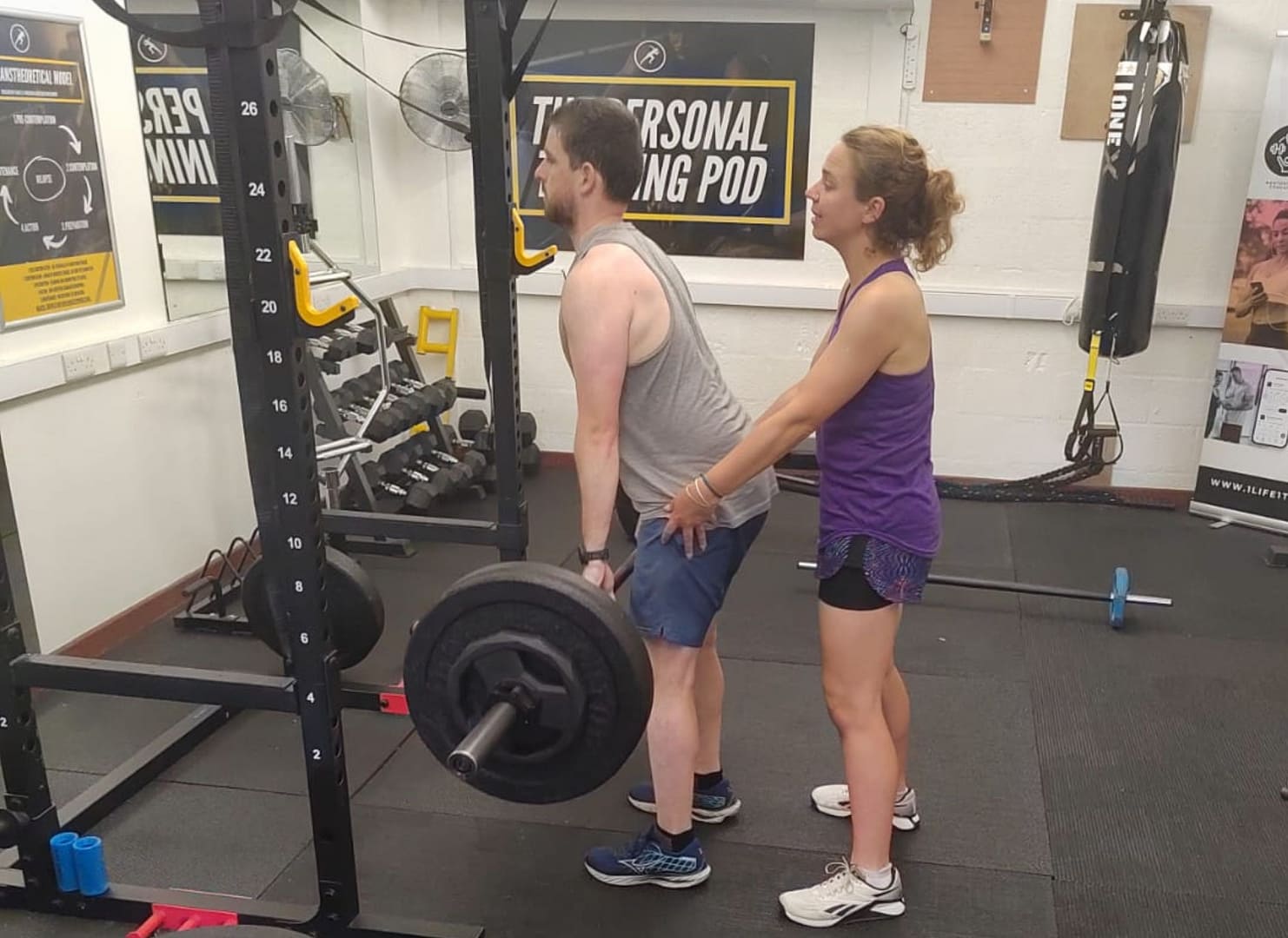 person deadlifting with coach