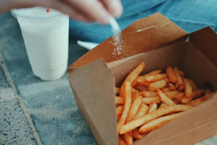person adding salt to box of chips