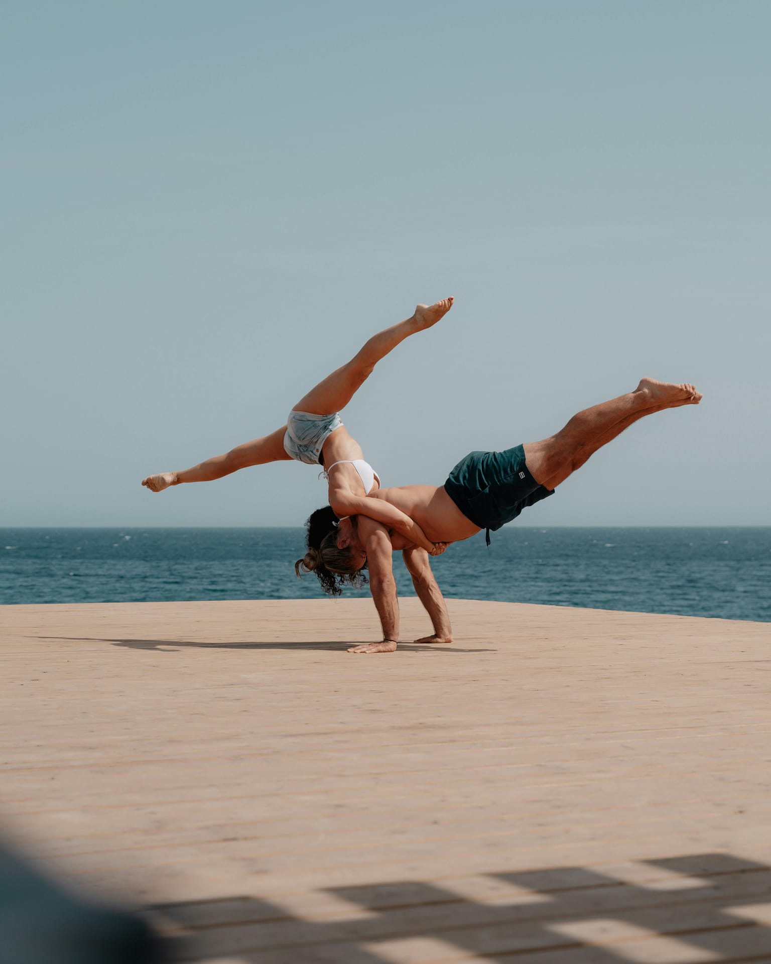 Woman doing a cartwheel over a horizontal man with his feet in the air